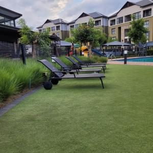 a row of benches sitting on the grass near a building at Prunell in midrand in Midrand