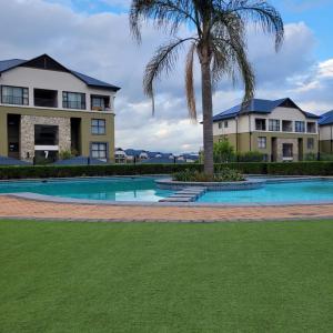a palm tree in front of a building with a swimming pool at Prunell in midrand in Midrand