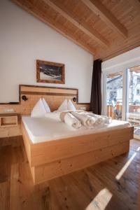 a bedroom with a large wooden bed with white sheets at Palazi Apartments & Spa in Nauders