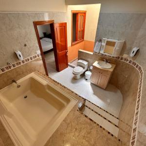 a bathroom with a tub and a toilet and a sink at Casa Hotel Los Fundadores in La Victoria