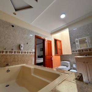 a bathroom with a large tub and a toilet at Casa Hotel Los Fundadores in La Victoria