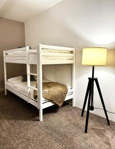 ein weißes Etagenbett in einem Zimmer mit einer Lampe in der Unterkunft Haus Gitta II in Luckenwalde