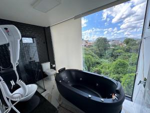 uma casa de banho com uma banheira preta e uma grande janela. em Pousada Circuito dos Inconfidentes em Congonhas