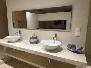 uma casa de banho com 2 lavatórios e um espelho grande em La Villa Samba Ngaparou em Ngaparou