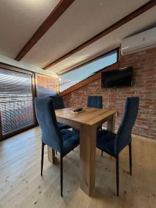 a wooden table with chairs in a room with a brick wall at Casa Norvegia Ohrid in Ohrid