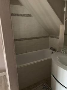 Baño blanco con bañera y lavamanos en Appartement Cosy, en Lamorlaye