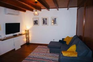 sala de estar con sofá azul y TV de pantalla plana en Casa da Cantarinha en Fundão