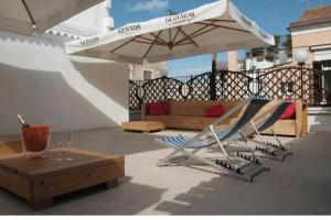 two lounge chairs and an umbrella on a patio at Saint Patrick-Guest House Del 1200 in Barletta