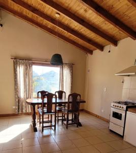 cocina con mesa, sillas y ventana en El Retamo en San Carlos de Bariloche