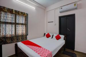 Un dormitorio con una cama con almohadas rojas y una ventana en OYO Flagship Hotel I stayz, en Madurai