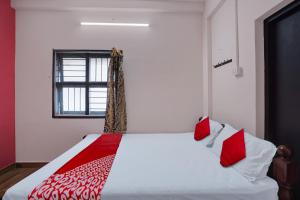 1 dormitorio con 1 cama con almohadas rojas y blancas en OYO Flagship Hotel I stayz, en Madurai