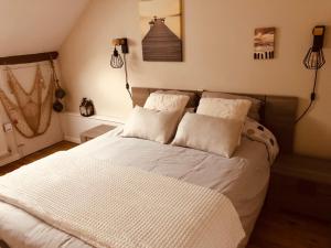 um quarto com uma cama com lençóis brancos e almofadas em Chambres d'Hôtes Bastia et Bonifacio em Retiers