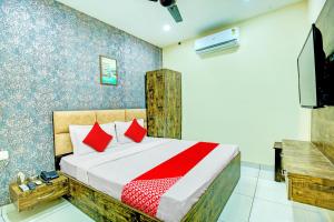 Schlafzimmer mit einem Bett mit roten Kissen und einem TV in der Unterkunft OYO Hotel Grace Villa in Ludhiana