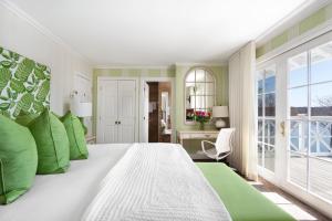 - une chambre avec un grand lit blanc et des oreillers verts dans l'établissement Manoir Hovey, Relais & Châteaux, à North Hatley