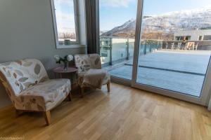 a room with two chairs and a table and a balcony at Strandkanten Panorama in Tromsø