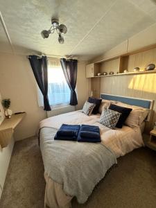 a bedroom with a large bed with blue pillows on it at Bayview Bliss - Luxury Holiday Caravan - Northumberland in Newbiggin-by-the-Sea