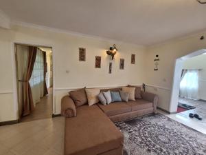 ein Wohnzimmer mit einem braunen Sofa in einem Zimmer in der Unterkunft Ol-tome Country House - Nakuru in Nakuru