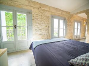 een slaapkamer met een bed in een kamer met ramen bij Le Platane de la canourgue in Montpellier