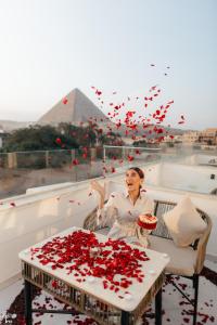 una mujer sentada en un balcón con una mesa llena de rosas en Shadow Pyramids Palace, en El Cairo