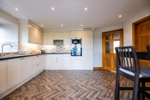 a kitchen with white cabinets and a wooden floor at Cosy cottage between the Lakes and Dales in Cowan Bridge