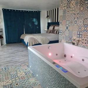 ein Badezimmer mit einer Badewanne und ein Schlafzimmer mit einem Bett in der Unterkunft L’Appar(T) du Grand Bois - Jacuzzi - in Soucelles