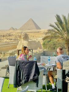 White House Pyramids View في القاهرة: يجلس شخصان على طاولة أمام الاهرامات