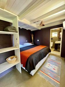 ein Schlafzimmer mit einem Bett mit einer orangen und schwarzen Bettdecke in der Unterkunft Vila Patí Caraíva in Caraíva
