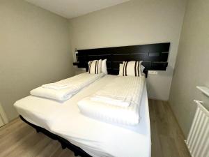 ein großes weißes Bett mit einem schwarzen Kopfteil in einem Zimmer in der Unterkunft Reykjavikurvegur 42 in Reykjavík