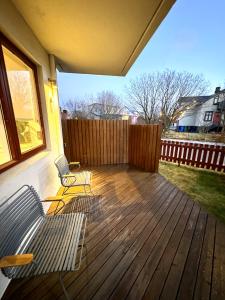 a wooden deck with two chairs and a fence at Reykjavikurvegur 42 in Reykjavík