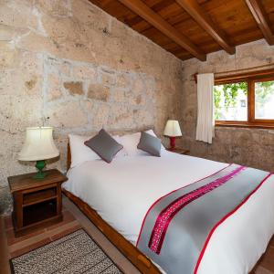 a bedroom with a large white bed with two lamps at Xani Mui in San Jerónimo Aculco
