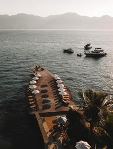 uma doca com guarda-sóis e barcos na água em Hotel Mercedes em Ilhabela