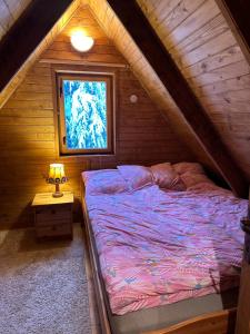 Bett in einem Holzzimmer mit Fenster in der Unterkunft Wichrowe Wzgórze 4 in Rajcza