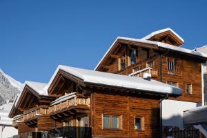 une maison en rondins avec de la neige sur le toit dans l'établissement Luf Lodges, à Ischgl