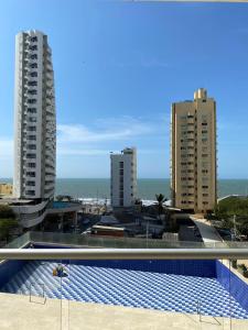 una piscina con dos edificios altos y el océano en Cartagena 3 habitaciones 9 personas cerca a la playa Wifi y Parqueadero, en Cartagena de Indias