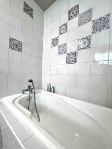 a white bath tub with a faucet in a bathroom at La Casa Del Papa - Maison spacieuse avec jardin in Dole