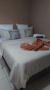 Una gran cama blanca con una manta naranja. en Mossie Inn Accommodation en Swakopmund