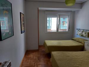 um quarto com duas camas e uma janela em Cimadevilla Apartamento San Pedro em Gijón