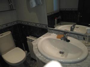 uma casa de banho com um lavatório branco e um WC. em Cimadevilla Apartamento San Pedro em Gijón