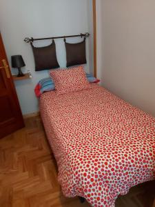 um quarto com uma cama com uma colcha vermelha e branca em Cimadevilla Apartamento San Pedro em Gijón