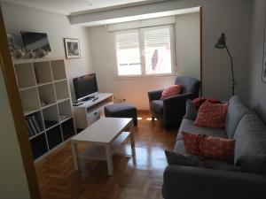 uma sala de estar com um sofá e uma mesa em Cimadevilla Apartamento San Pedro em Gijón