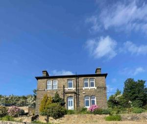 a brick house on a hill with a blue sky at 2 Victoria Place - Luddendenfoot in Luddenden Foot