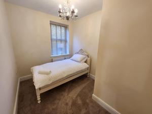 a small bedroom with a bed and a chandelier at 2 Victoria Place - Luddendenfoot in Luddenden Foot