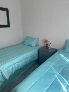 2 letti in una camera con cuscini blu e un tavolo di Hermoso condominio en Cd. Juárez, Chih. Céntrico a Ciudad Juárez