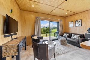a living room with a table and a couch and a television at Kūkū Kabin - Waimate North Eco Holiday Cabin in Kerikeri