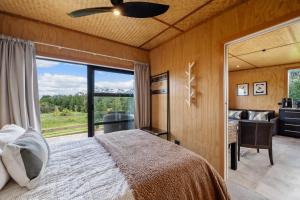 a bedroom with a bed and a large window at Kūkū Kabin - Waimate North Eco Holiday Cabin in Kerikeri