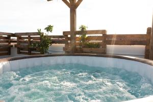 a jacuzzi tub on a patio with benches at Secret Paradise & SPA Rooftop in Quartu SantʼElena