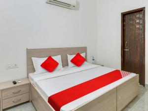 1 dormitorio con 1 cama grande con almohadas rojas en OYO Hotel Classic in, en Mohali