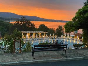 a park bench in front of a swimming pool at sunset at AJ Apartment 2, Santa Marina Holiday Village, Sozopol in Sozopol