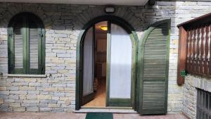 una entrada a un edificio de ladrillo con persianas verdes en Casa Aprica piste da sci Baradello en Aprica