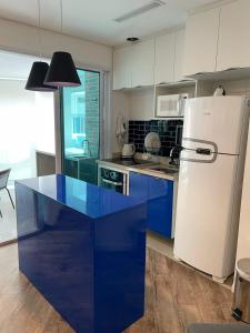 eine Küche mit einem blauen Tisch und einem Kühlschrank in der Unterkunft Estanconfor Santos 705 com estacionamento GRÁTIS in Santos